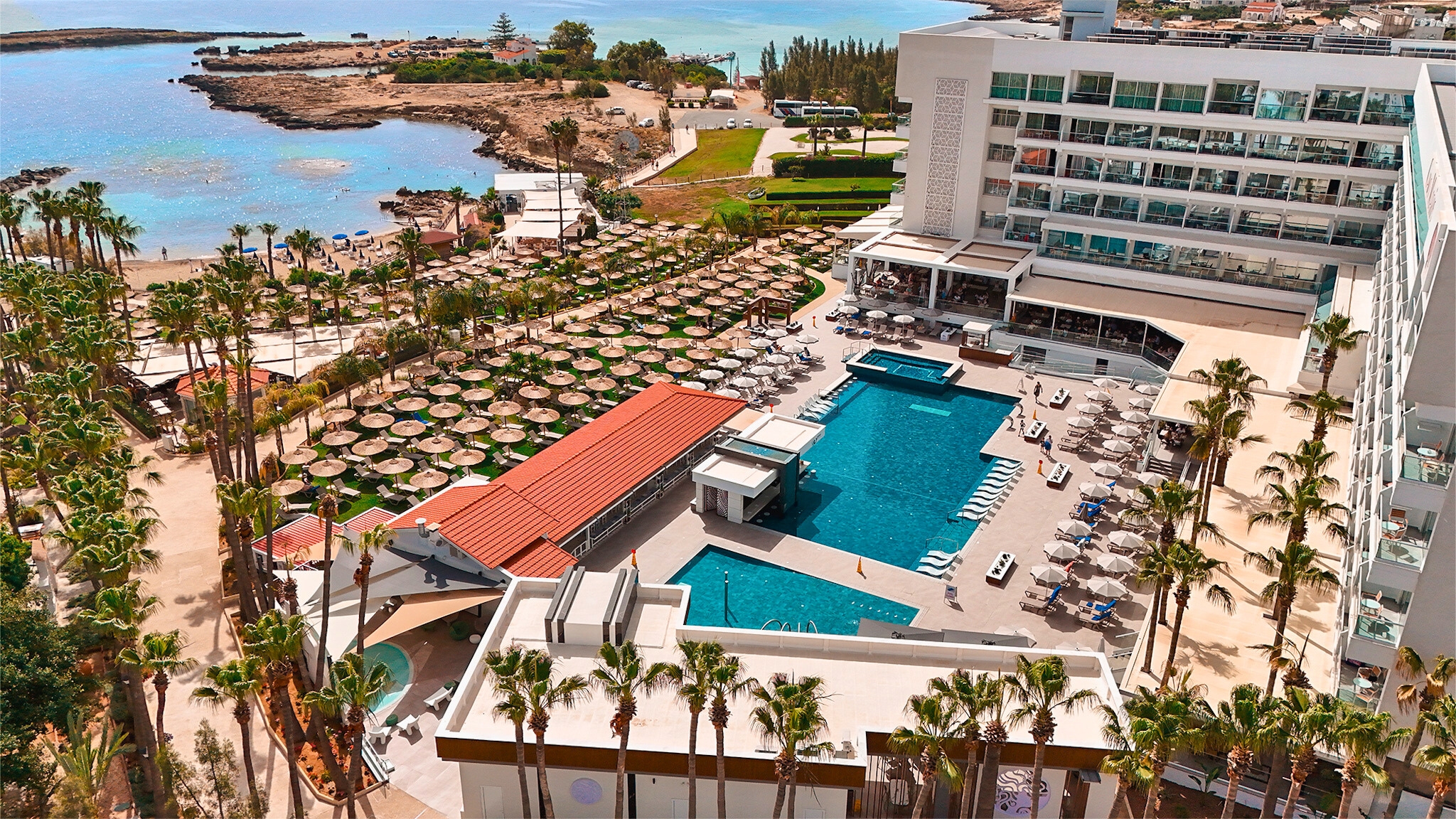 Cavo Maris Beach Hotel mit Palmen und direktem Strandzugang